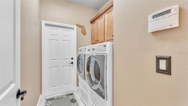 clothes washing area featuring washing machine and dryer, light tile patterned floors, and cabinet space