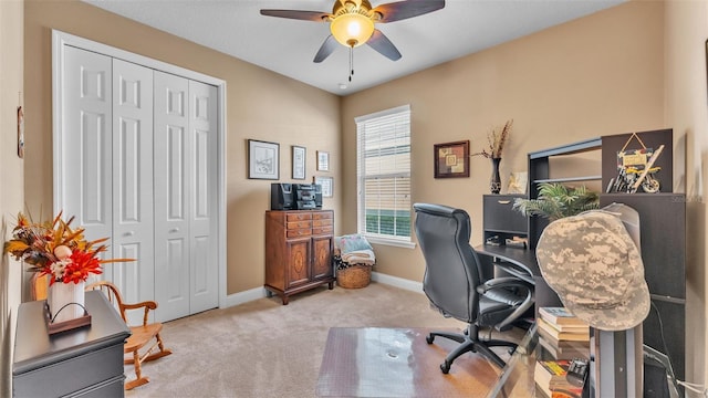 carpeted office space featuring ceiling fan and baseboards