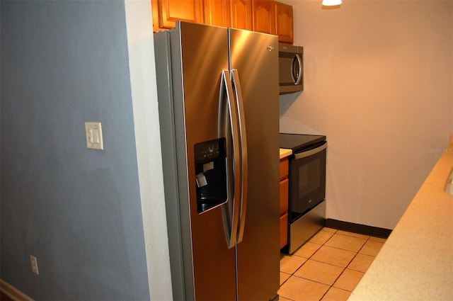 255 S Pennsylvania Ave, Lake Alfred, FL 33850 - kitchen featuring stainless steel appliances, light countertops, light tile patterned floors, and brown cabinetry
