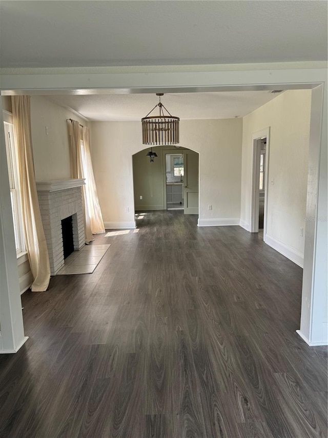 1217 King Ave, Lakeland, FL 33803 - unfurnished living room featuring arched walkways, baseboards, dark wood-style flooring, and a fireplace
