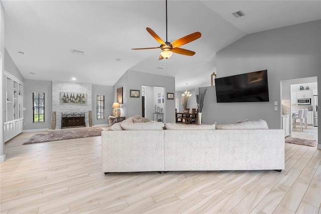 7313 Crape Myrtle Way, Sarasota, FL 34241 - living room with vaulted ceiling, a ceiling fan, a large fireplace, light wood finished floors, and a chandelier
