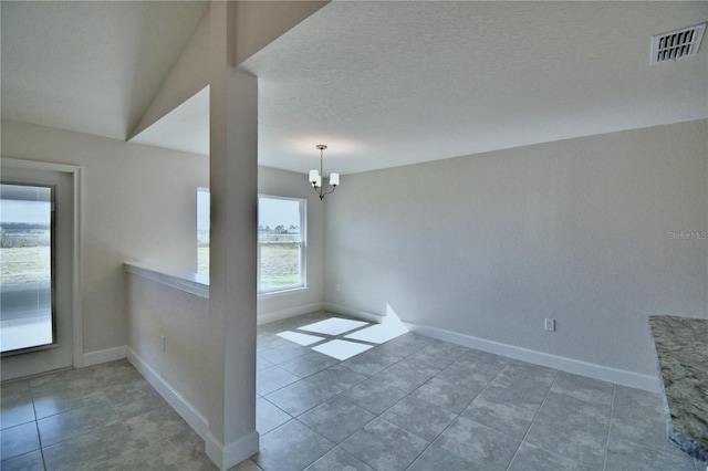 spare room with a chandelier, baseboards, and tile patterned flooring
