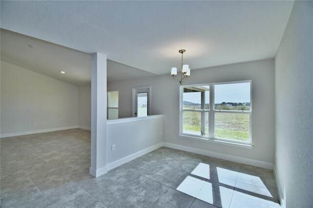 tiled empty room with plenty of natural light, a chandelier, and baseboards