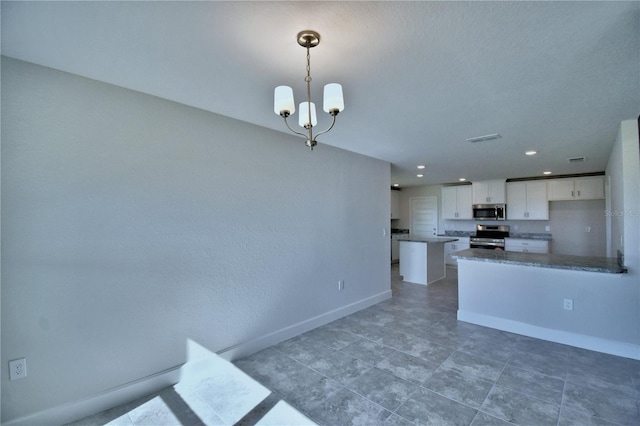 kitchen featuring stainless steel appliances, white cabinets, baseboards, a chandelier, and dark countertops
