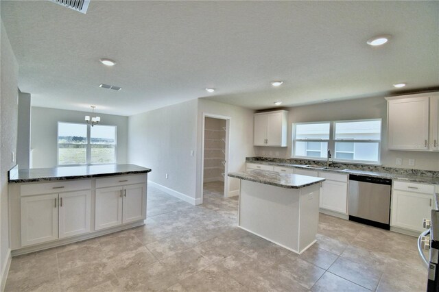 kitchen featuring stainless steel dishwasher, stone countertops, plenty of natural light, white cabinetry, and recessed lighting