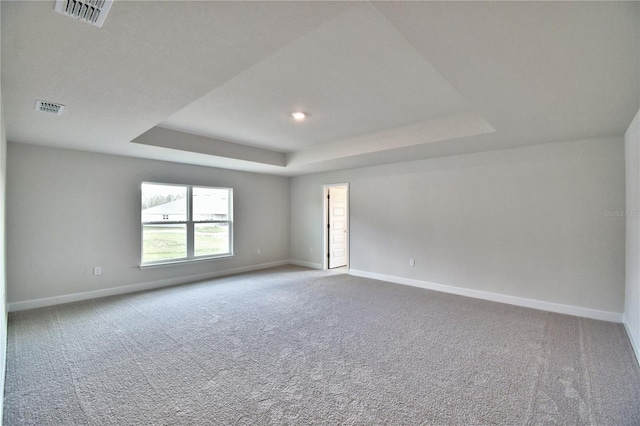 empty room featuring a raised ceiling, baseboards, carpet, and recessed lighting