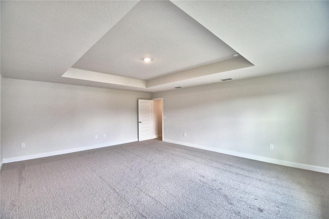 unfurnished room with a tray ceiling, baseboards, and carpet floors
