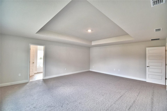 empty room with a tray ceiling, carpet flooring, baseboards, and recessed lighting