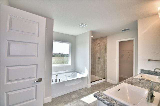 full bathroom featuring a shower stall, a spacious closet, a garden tub, baseboards, and tile patterned flooring