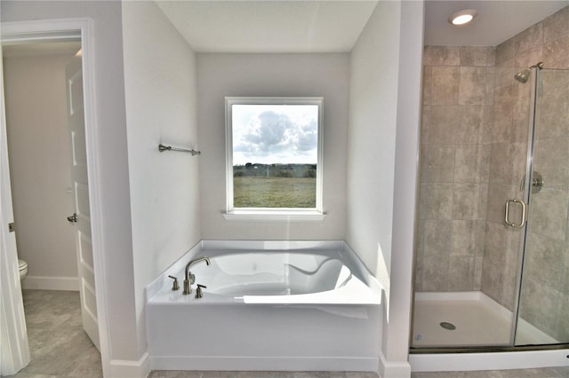 bathroom featuring a stall shower, a garden tub, toilet, and tile patterned floors