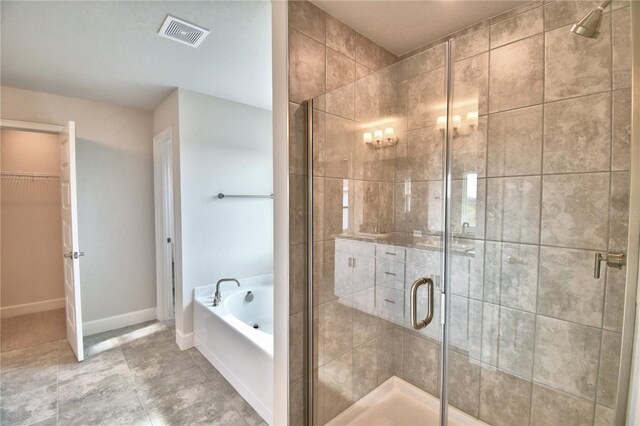 bathroom with a stall shower, a bath, a walk in closet, and baseboards