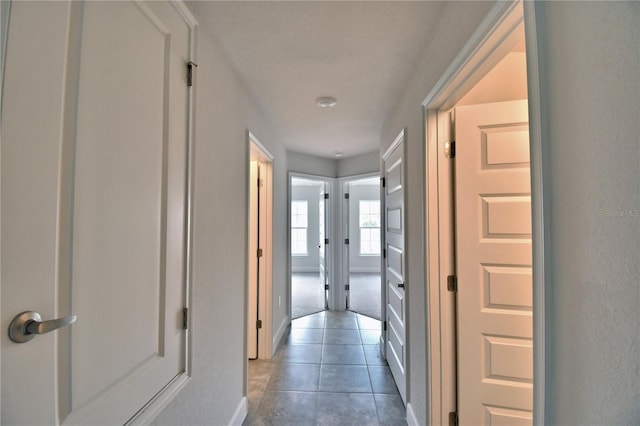corridor with tile patterned floors and baseboards