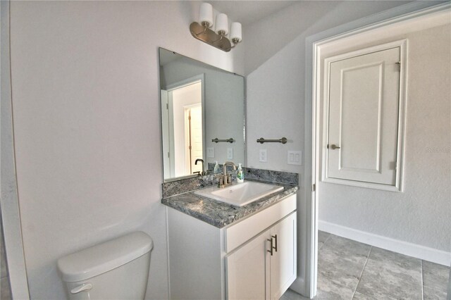 half bathroom featuring toilet, vanity, baseboards, and tile patterned floors