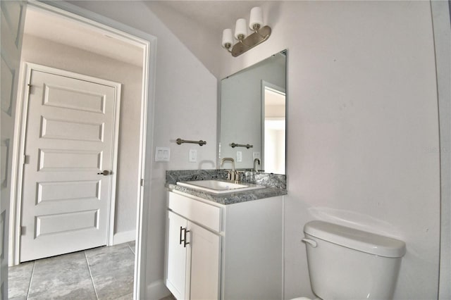 half bath with toilet, vanity, and tile patterned floors