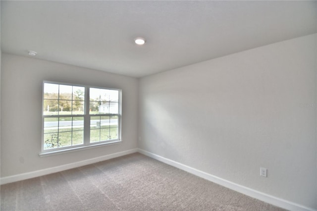 unfurnished room featuring baseboards, carpet, and a smoke detector