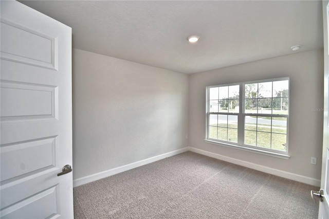 spare room with baseboards and carpet
