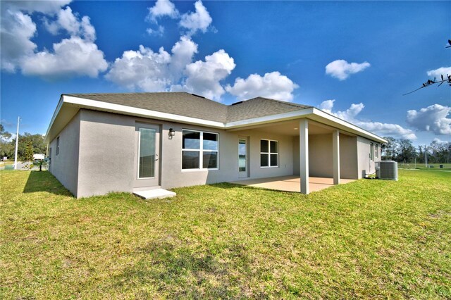 rear view of property with central air condition unit, a patio, stucco siding, and a yard