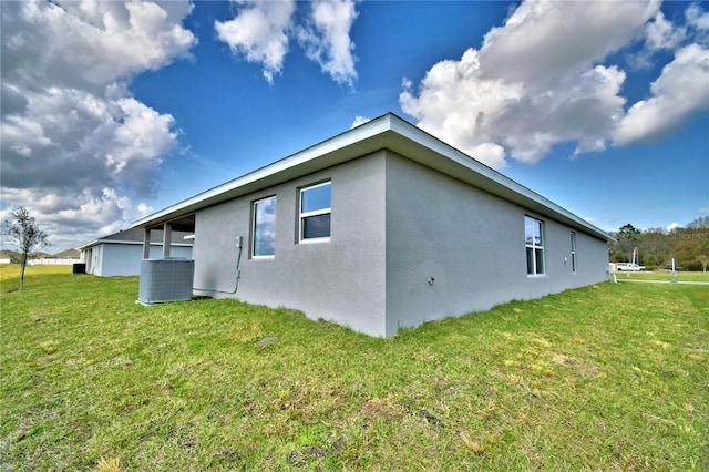 view of home's exterior with stucco siding, cooling unit, and a yard