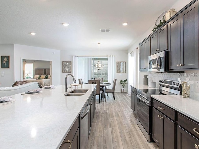 kitchen with a sink, dark brown cabinetry, light wood-type flooring, visible vents, and appliances with stainless steel finishes