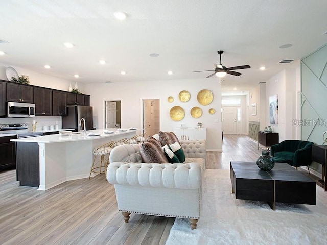 living room featuring ceiling fan, light wood-type flooring, visible vents, and recessed lighting