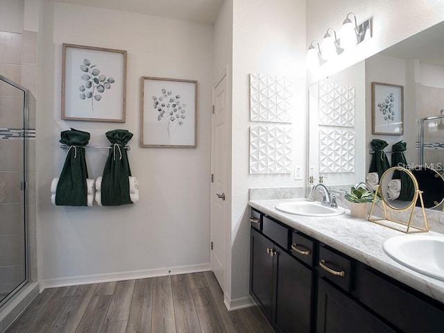 bathroom featuring a sink, double vanity, a stall shower, and wood finished floors