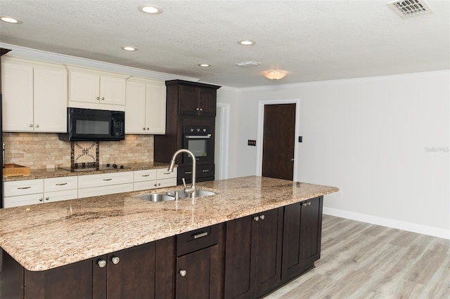 4008 S Carlisle Rd, Lakeland, FL 33813 - kitchen with black appliances, light wood-type flooring, crown molding, decorative backsplash, and a center island with sink