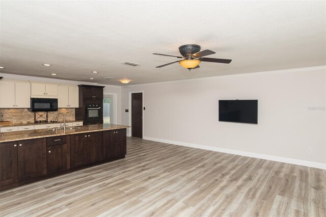 4008 S Carlisle Rd, Lakeland, FL 33813 - kitchen featuring black appliances, open floor plan, dark brown cabinets, tasteful backsplash, and light wood-style floors