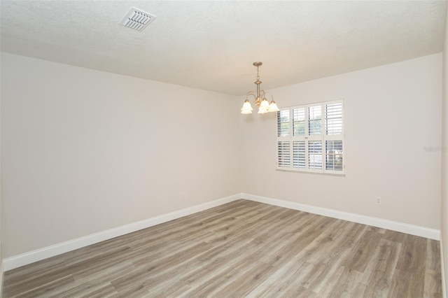 4008 S Carlisle Rd, Lakeland, FL 33813 - spare room with light wood finished floors, a chandelier, and a textured ceiling