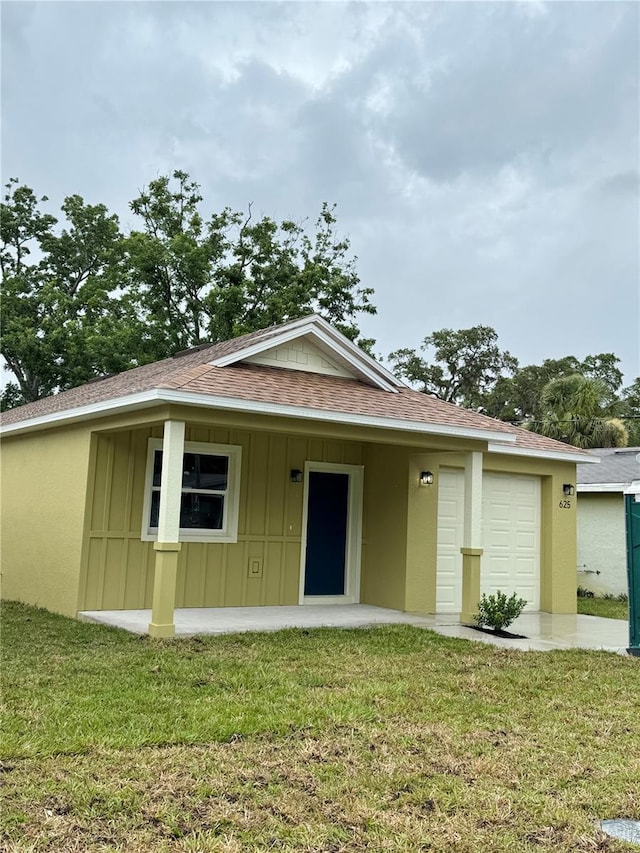 625 W 9th St, Lakeland, FL 33805 - view of front of property with a shingled roof, a front lawn, a garage, and board and batten siding