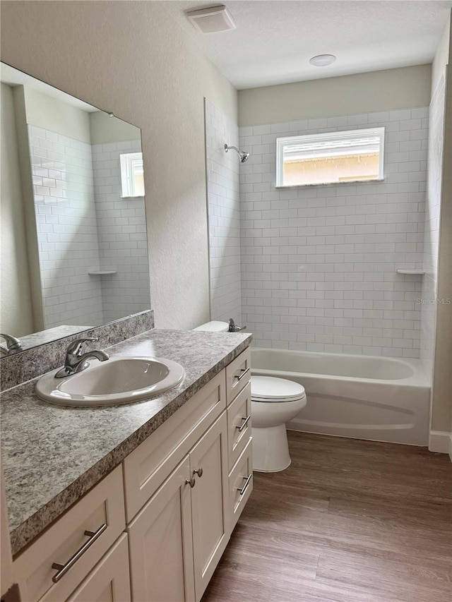 625 W 9th St, Lakeland, FL 33805 - bathroom featuring vanity, toilet, shower / bath combination, wood finished floors, and a textured wall
