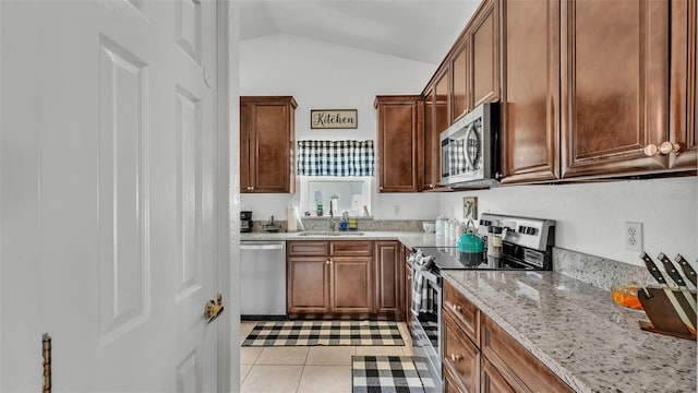 242 Kings Pond Ave SW, Winter Haven, FL 33880 - kitchen with stainless steel appliances, lofted ceiling, a sink, light stone countertops, and light tile patterned floors