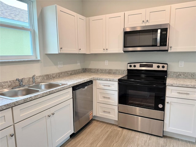 629 W 9th, Lakeland, FL 33805 - kitchen featuring stainless steel appliances, a sink, white cabinets, and light wood-style flooring