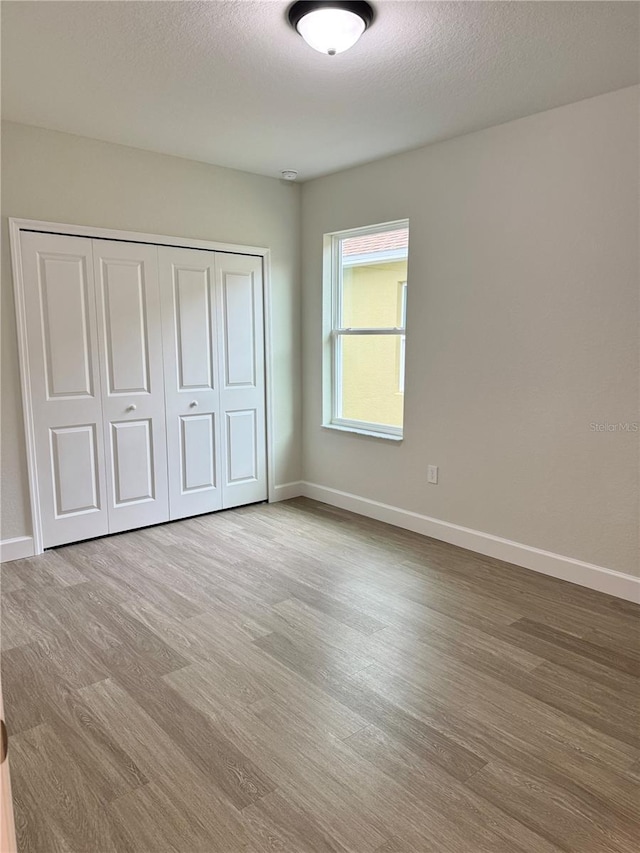 629 W 9th, Lakeland, FL 33805 - unfurnished bedroom with wood finished floors, baseboards, a closet, and a textured ceiling
