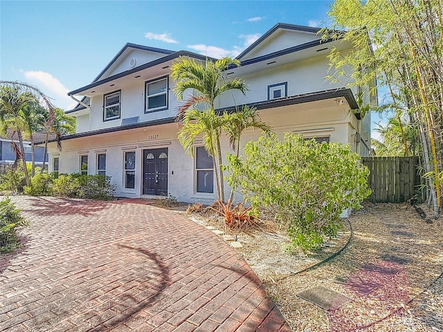 view of front of house featuring stucco siding and fence