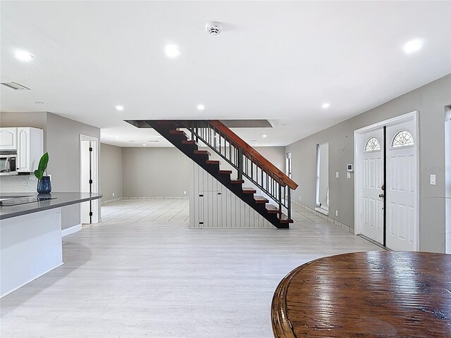 foyer featuring light wood-style flooring, recessed lighting, baseboards, visible vents, and stairway