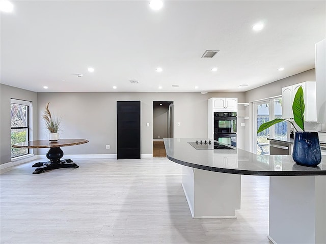 kitchen featuring black appliances, visible vents, white cabinetry, a wealth of natural light, and light wood-style floors