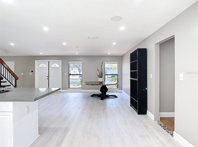 foyer featuring baseboards, light wood-style floors, and stairway