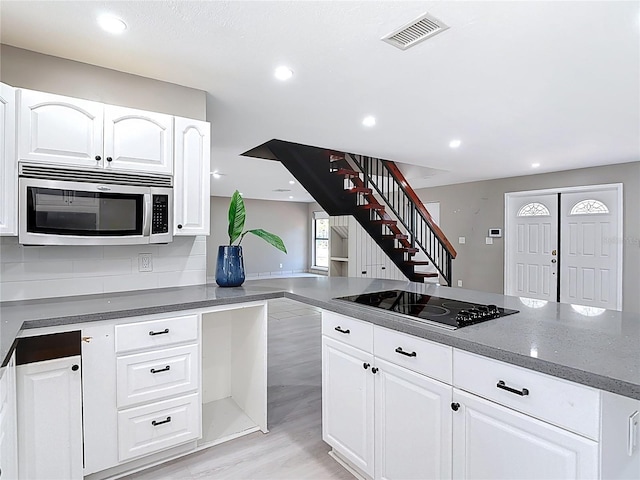 kitchen with stainless steel microwave, visible vents, recessed lighting, white cabinets, and black electric cooktop