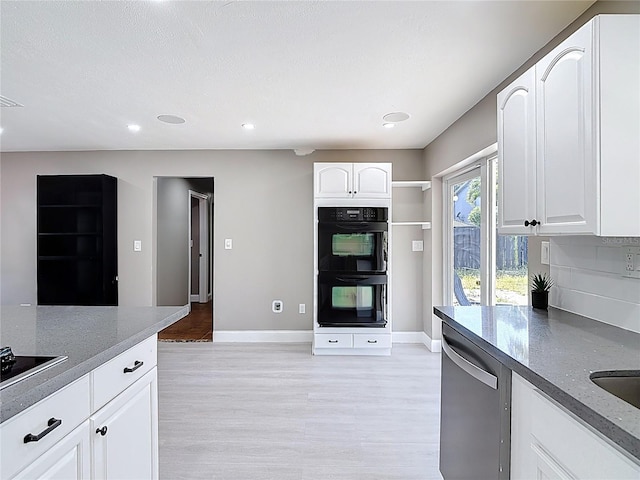 kitchen featuring stainless steel dishwasher, light wood-style floors, dobule oven black, and baseboards