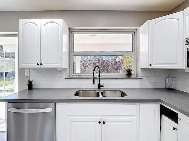 kitchen with a sink, stainless steel appliances, tasteful backsplash, and dark countertops