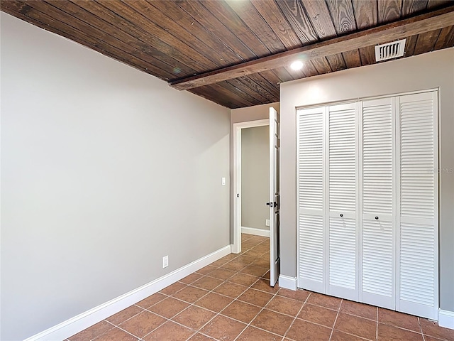 unfurnished bedroom with baseboards, visible vents, wooden ceiling, and dark tile patterned floors