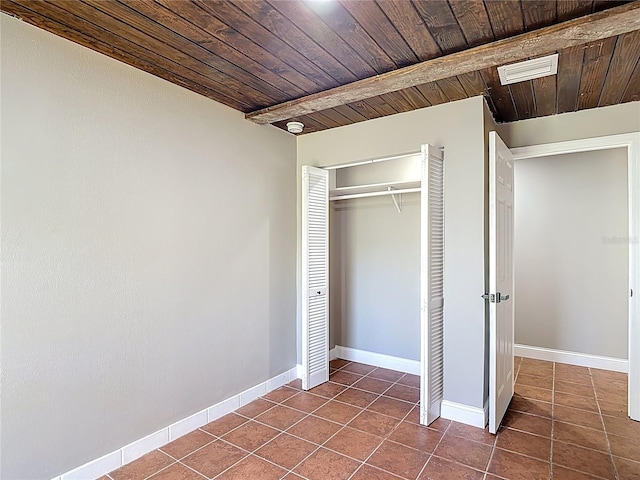 unfurnished bedroom featuring wooden ceiling, dark tile patterned flooring, and visible vents