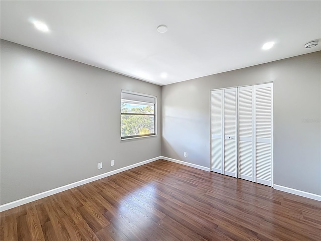 unfurnished bedroom with baseboards, recessed lighting, dark wood finished floors, and a closet