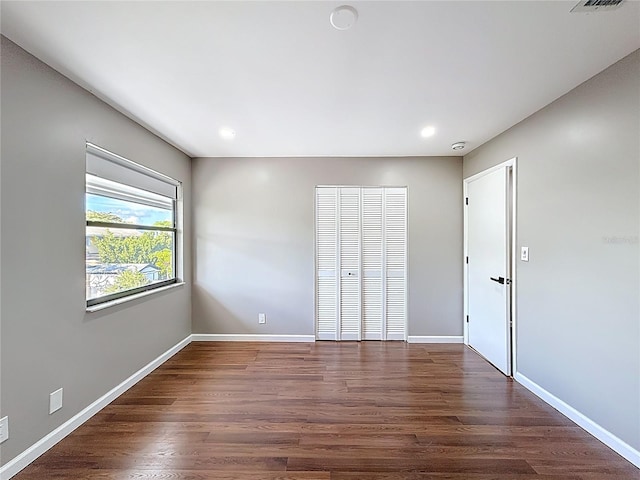 unfurnished bedroom featuring baseboards, dark wood-style flooring, a closet, and recessed lighting
