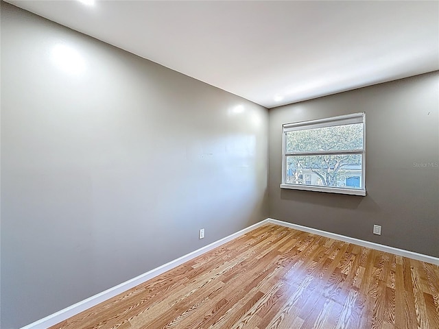 unfurnished room with baseboards and wood finished floors