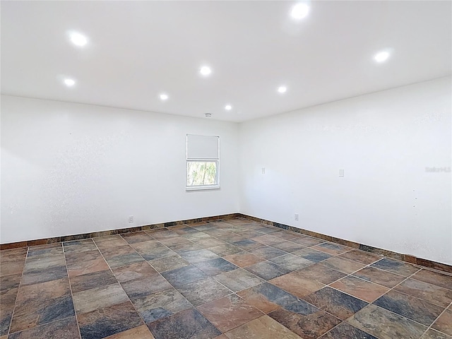 empty room with baseboards, stone finish flooring, and recessed lighting