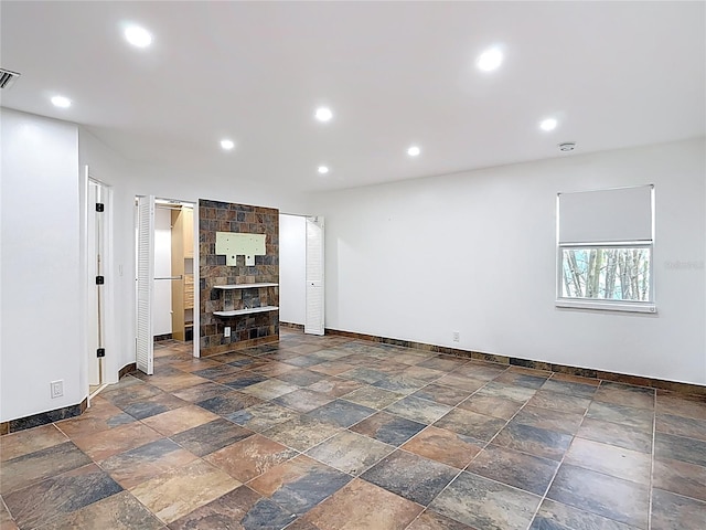 basement with recessed lighting, visible vents, baseboards, and stone tile floors