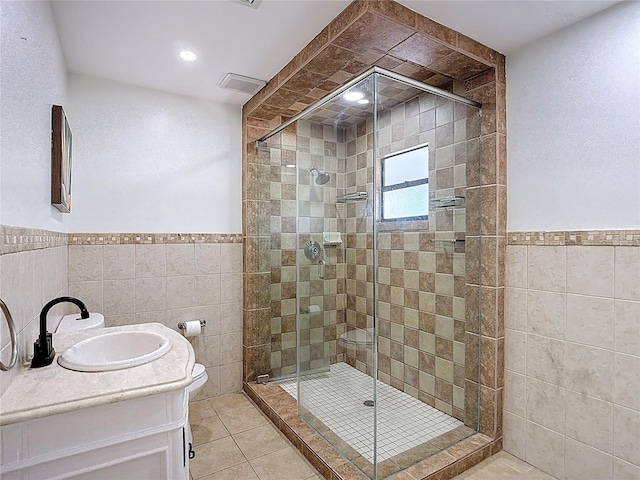 bathroom featuring a shower stall, tile walls, tile patterned flooring, and wainscoting