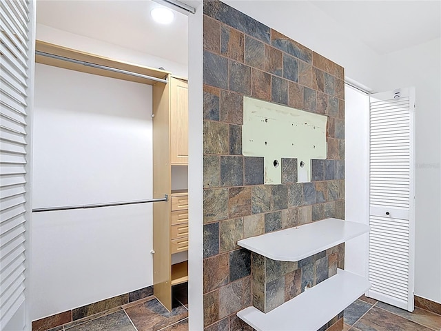 bathroom with stone tile floors and baseboards