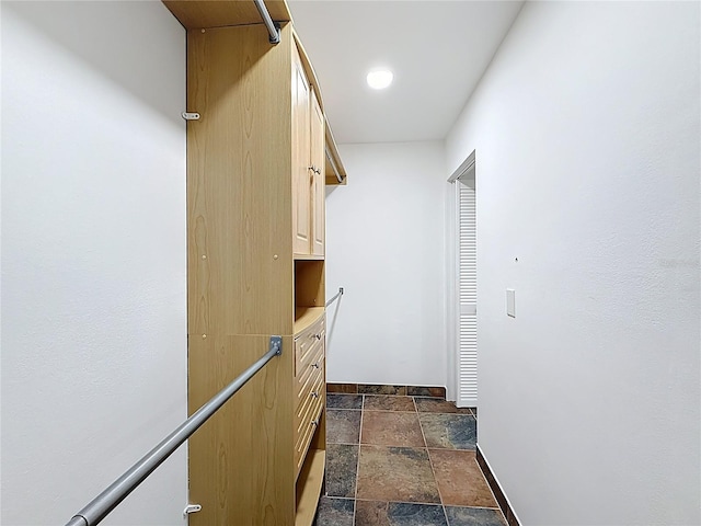 hall featuring stone tile floors and baseboards